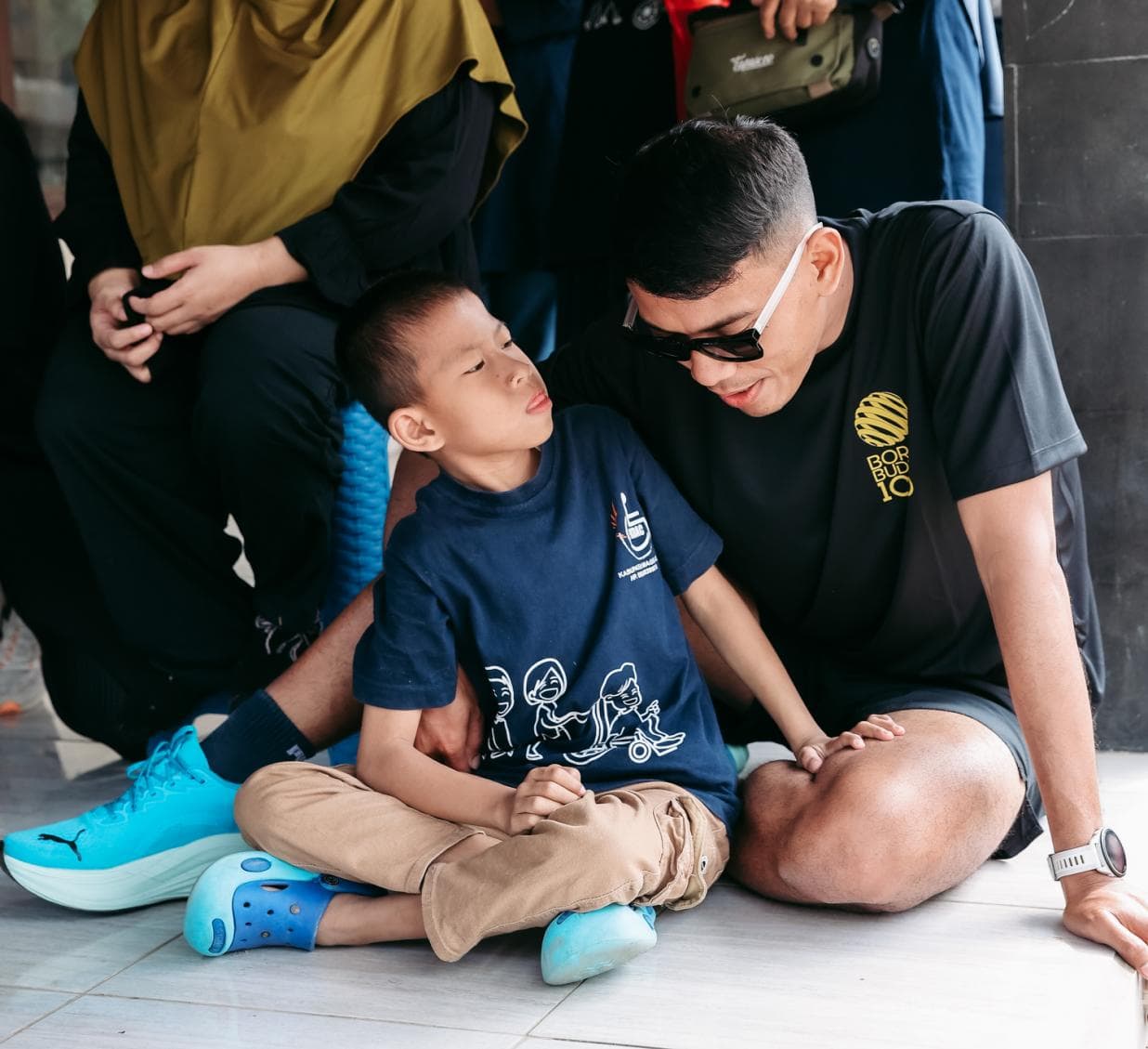 Pelari BOROBUDUR100 duduk bersama seorang anak